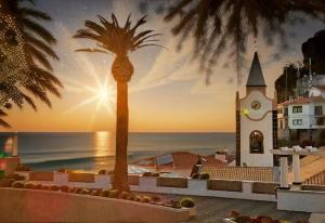 a view of the ocean and a church with a palm tree at Paradise Valley Ponta do Sol in Ponta do Sol