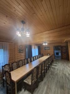 a long table with chairs in a room with wooden ceilings at FAMILY еко номери та будинки in Yablunytsya