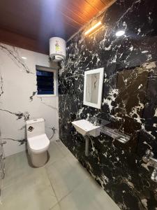 uma casa de banho em mármore preto com um WC e um lavatório em le hut residency em Pondicherry mais 1 fotografia