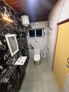 um banheiro com vaso sanitário, pia e espelho em le hut residency em Pondicherry