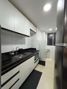 a kitchen with white cabinets and a black counter top at Refúgio na praia - Ap para locação por temporada in Parnamirim