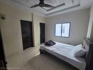 een slaapkamer met een bed met een plafondventilator bij Star Residence in Karachi