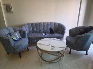een woonkamer met een bank, twee stoelen en een tafel bij Star Residence in Karachi