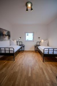 two beds in a room with wooden floors and a window at betterplaces Homes - Frontenhausen in Frontenhausen