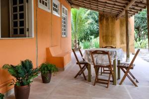 a patio with a table and chairs on a house at Casa Coqueville - Charmosa, tranquila e cercada pela natureza em Itacaré in Itacaré