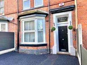ein Backsteinhaus mit einer schwarzen Tür und zwei Fenstern in der Unterkunft Yastayzzz at Apartment 4 Worcester House in Worcester