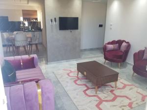 a living room with purple furniture and a flat screen tv at Appartement Oasis Chenini Gabes in Shanīnī