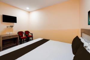 勒克瑙Hotel O Chandra banquets的一间卧室配有一张床、一张桌子和两把椅子