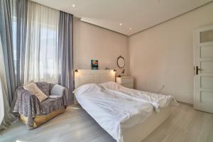 a bedroom with a bed and a chair and a window at Heart of Sofia 2 Bdr Elevator Balcony Relax in Sofia