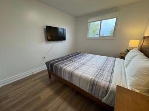 a bedroom with a bed and a flat screen tv at North Barrie !E Stylish and Cozy Private Bedroom with Shared Bathroom in Barrie
