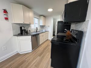 a kitchen with black appliances and white cabinets at North Barrie !E Stylish and Cozy Private Bedroom with Shared Bathroom in Barrie