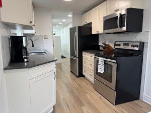 a kitchen with black appliances and white cabinets at North Barrie !E Stylish and Cozy Private Bedroom with Shared Bathroom in Barrie +7 photos