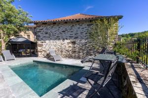 a pool with chairs and a table and a building at Gîte de Prestige dans un Fort, Jacuzzi, 8 pers in Leynhac