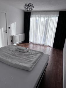 ein weißes Bett in einem Zimmer mit einem großen Fenster in der Unterkunft Sarajevo Soul in Sarajevo