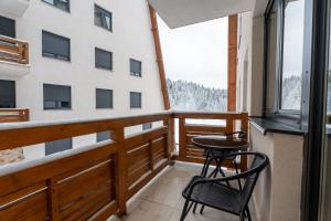 a balcony with a table and chairs and a building at 108 Lux Apartman Ravna planina in Gornje Pale