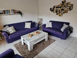 a living room with two purple couches and a coffee table at Hirschblick Apartments Willingen in Brilon +68 photos