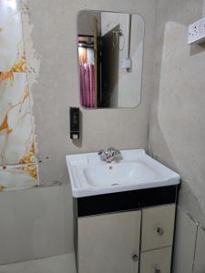 um banheiro com uma pia e um espelho em Amangarh Corbett Farmstay em Rehar