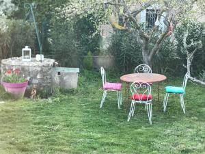 een tafel en vier stoelen in een tuin bij Maison individuelle avec piscine privée in Peyruis