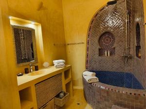 a bathroom with a large tub and a sink at La Douiria Essaouira Medina in Essaouira