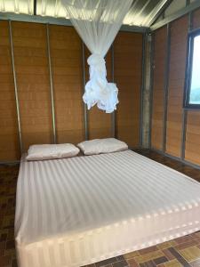 บ่อแก้วโฮมสเตย์的房间里有一张大床，挂着白色窗帘。