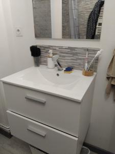 ein weißer Waschtisch mit Waschbecken und Spiegel in der Unterkunft Petit nuit doullet in La Grande-Motte