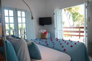 a room with a bed with red roses on it at Praiagogi Boutique Pousada in Maragogi