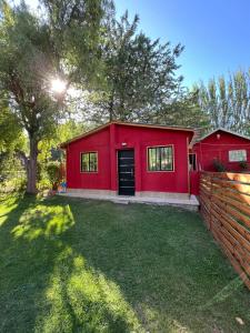 a red house in a yard with a fence at Complejo el trébol in Potrerillos