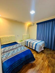 Casa Hohenau, Colonias Unidas في Hohenau: سريرين في غرفة مع ستائر زرقاء وأرضيات خشبية