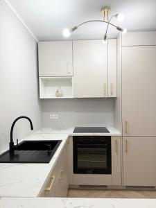 a white kitchen with a sink and a stove at Apartament Comfort Wrocław in Wrocław