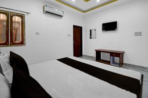 ein weißes Zimmer mit einem Bett und einem Tisch in der Unterkunft Hotel O DP Palace in Banthra Sikandarpur