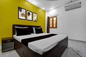 ein Schlafzimmer mit einem großen Bett mit einer gelben Wand in der Unterkunft Hotel O DP Palace in Banthra Sikandarpur