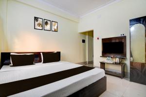 a hotel room with a large bed and a television at POP 84116K Hotel O Maa Tara Guest House in Dum-Dum Junction