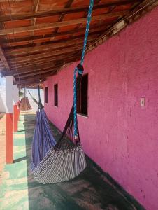 deux hamacs suspendus à un bâtiment rose dans l'établissement Hostel Mamitchesca - Redes e Barracas, à Aracati 8 autres photos