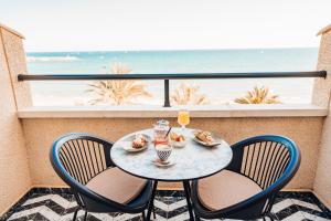 einen Tisch und Stühle auf einem Balkon mit Blick auf den Strand in der Unterkunft JovA Hotel Boutique in El Campello