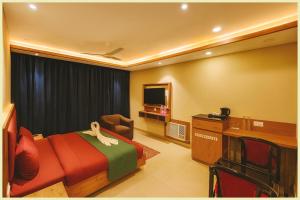 a bedroom with a bed and a chair and a television at Hotel THE RB Near Jagannath Temple And Sea Beach - Parking- Spa With Restaurant - SWIMMING POOL Facilities - Fully Air Conditioning Deluxe Rooms - Prime Location in Puri