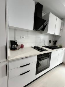 Una cocina con gabinetes blancos y un horno de estufa. en Appartement à louer, en Sousse