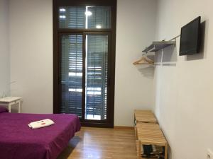 sypialnia z fioletowym łóżkiem i oknem z okiennicami w obiekcie Hostal Delfos w Barcelonie