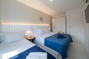 een slaapkamer met 2 bedden met blauwe lakens bij Lindo Apto, Prédio beira mar c/ Piscina e Hidro in Cabo Frio +69 foto's