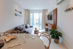 een woonkamer met een tafel en een bank bij Lindo Apto, Prédio beira mar c/ Piscina e Hidro in Cabo Frio