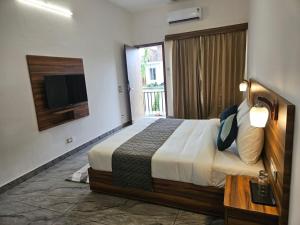 una camera d'albergo con un letto e una televisione di Corbett Crown Resort a Ramnagar