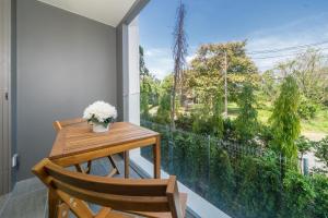 einen Balkon mit einem Holztisch und einem großen Fenster in der Unterkunft Phuket Family apartment in Phuket