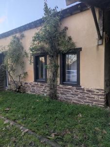 a house with two windows and a tree in the yard at Suite indépendante avec salle de bain à la campagne in Mordelles