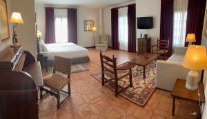Una habitación de hotel con una cama y una sala de estar. en Parador de Plasencia, en Plasencia