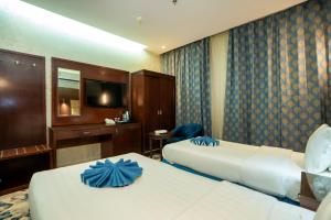 ein Hotelzimmer mit zwei Betten und einem Fernseher in der Unterkunft فندق جوهرة المقام الحمراء in Dschidda