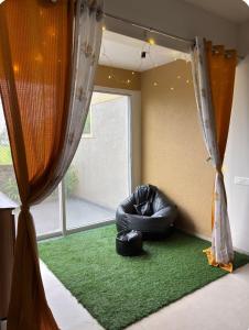 a black bean bag chair on a green rug next to a window at Staymisty igatpuri in Igatpuri