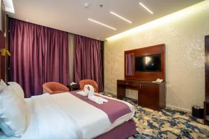 ein Hotelzimmer mit einem Bett und einem Fernseher in der Unterkunft فندق جوهرة المقام الحمراء in Dschidda