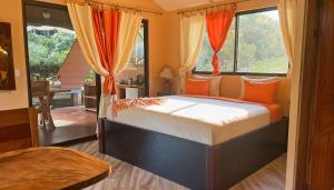 a bedroom with a large bed with orange pillows at Mei Tai Cacao Lodge in Bijagua +78 photos