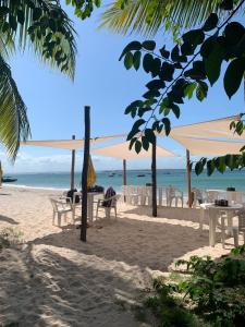 een strand met tafels en stoelen en de oceaan bij Casa Gêmeos in Cayru