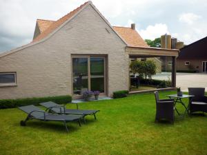 een tuin met stoelen en tafels en een huis bij Hoveke Paddebroek in Alveringem