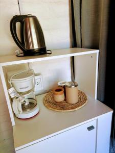 una cafetera y dos tazas en un estante en La Herradura, en Calingasta